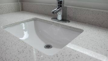 Un baño moderno con un lavamanos rectangular, grifo cromado y encimera con motas.
