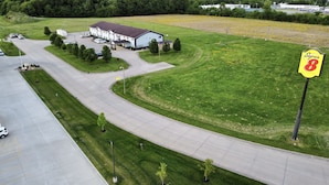 An aerial view of a building with a parking lot, a grassy field, and a sign for 'Super 8 by Wyndham'.