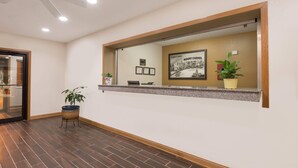 A reception area with a wooden reception desk, framed certificates, and a potted plant.