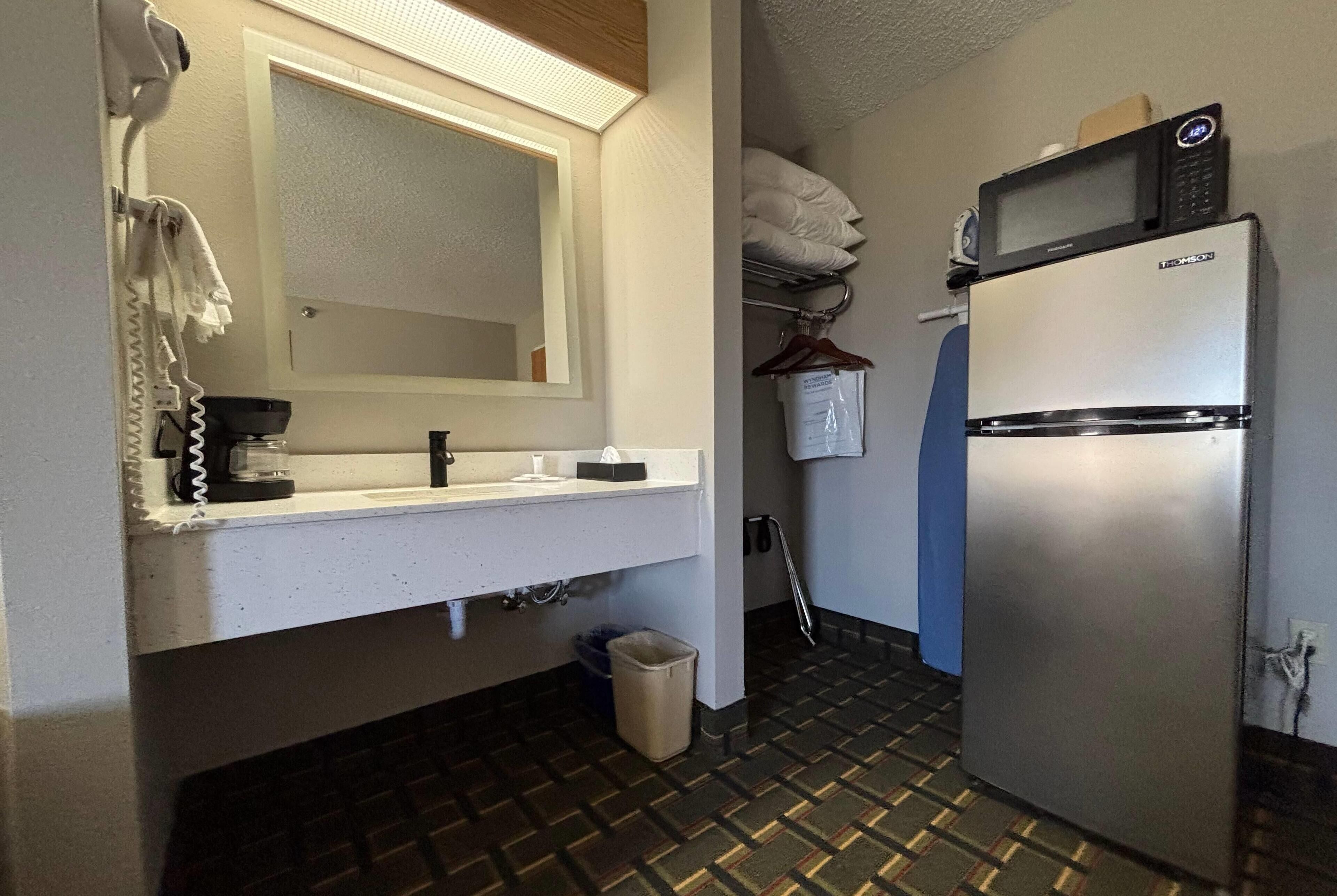Une petite salle de bain comprenant un lavabo, un miroir et un réfrigérateur.