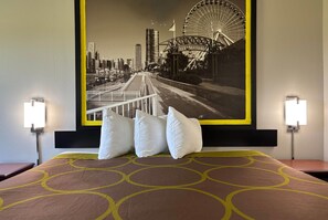 A hotel room with a bed, pillows, a headboard, and a large cityscape poster on the wall. - Super 8 by Wyndham Mt. Carmel IL (Mount Carmel)