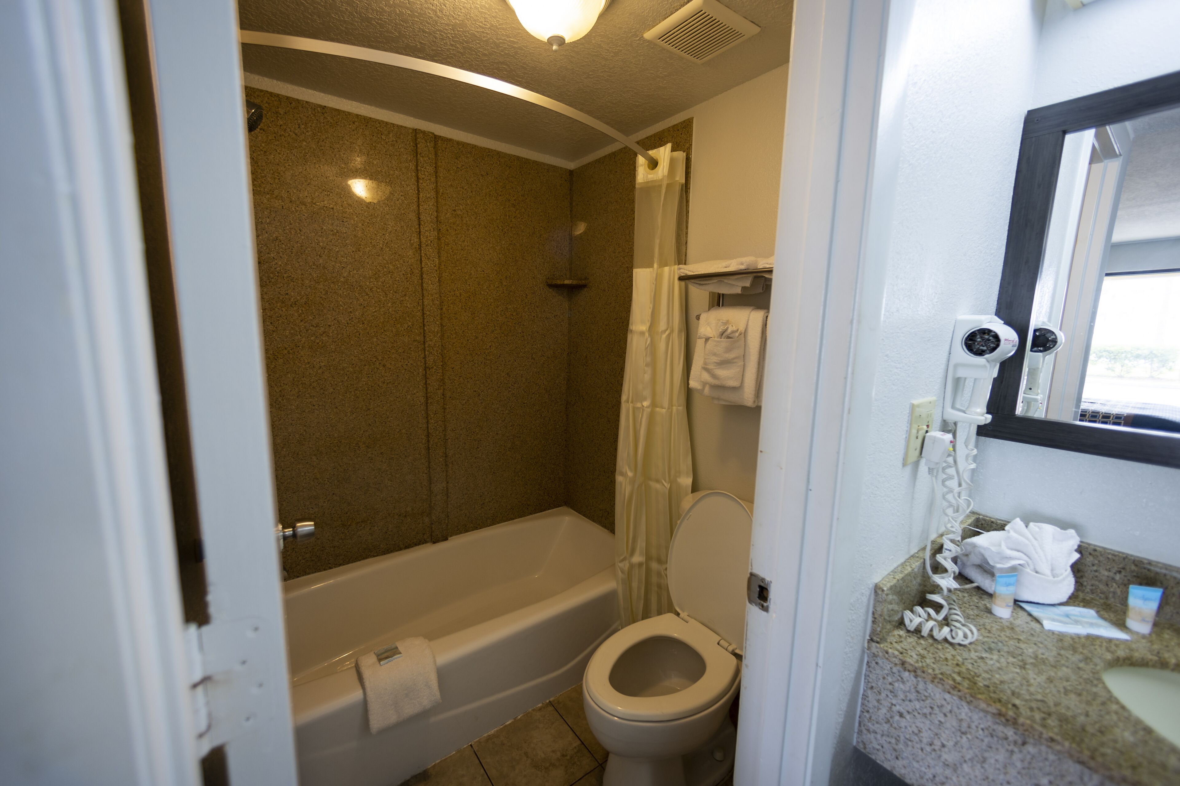 A bathroom with a bathtub, toilet, and a sink with a mirror.