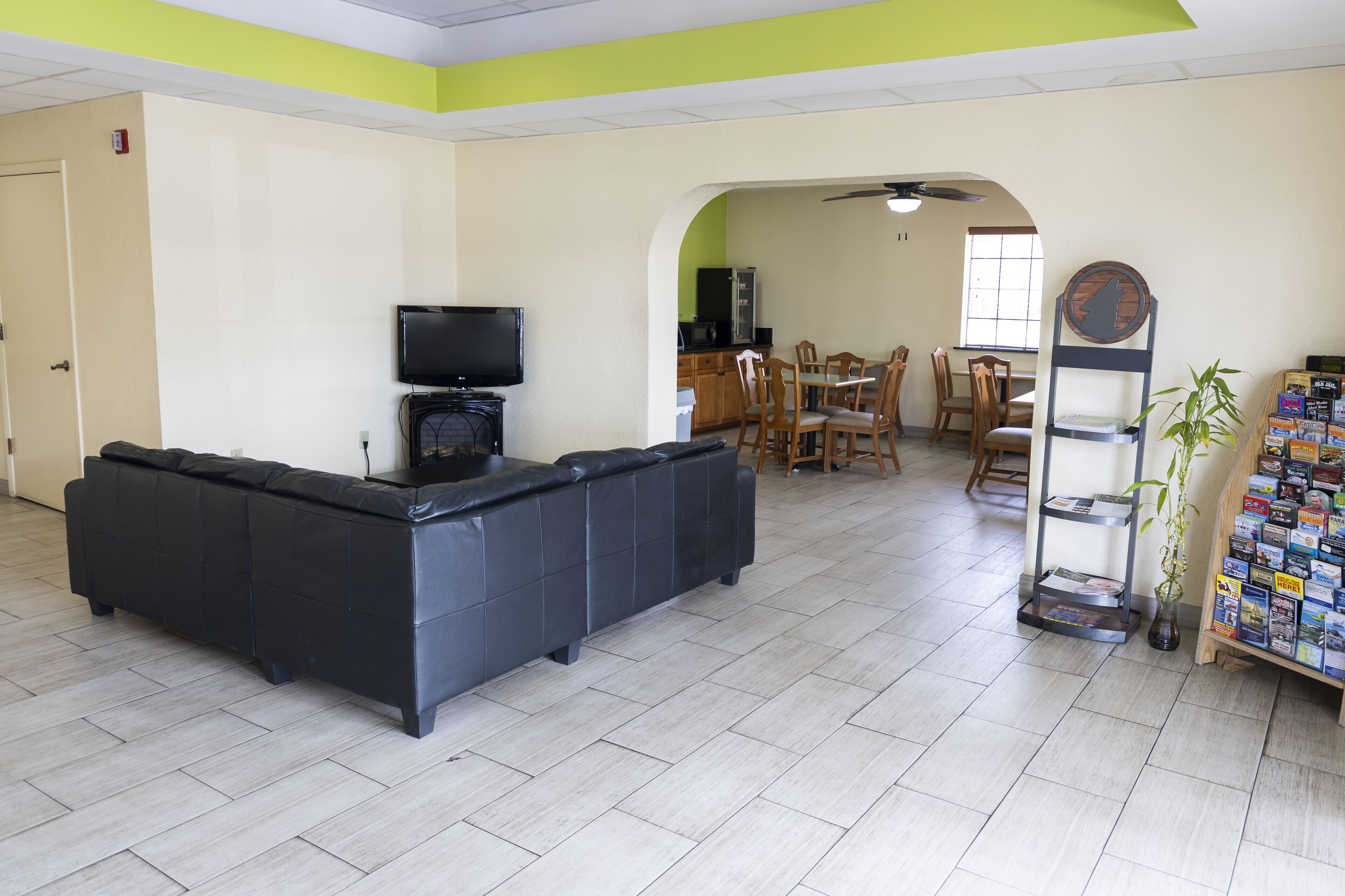 Una sala de estar con un sofá seccional negro, un televisor y una estantería con revistas.