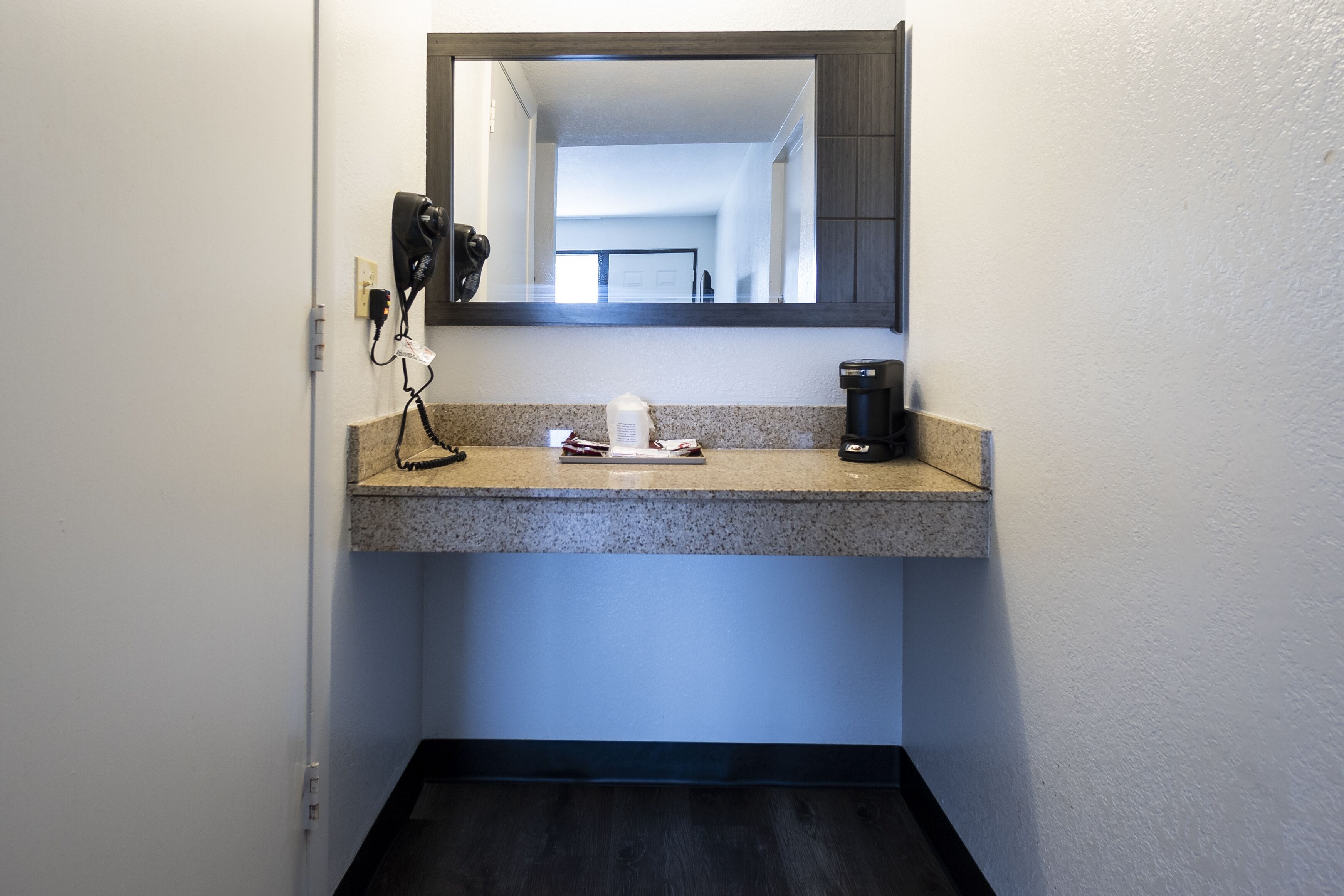 Une salle de bain dotée d’un comptoir en granit, d’une machine à café et d’un sèche-cheveux branché.