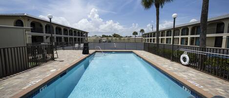 A rectangular swimming pool with a depth marker of 5 feet 9 inches, surrounded by a brick deck and a metal railing.