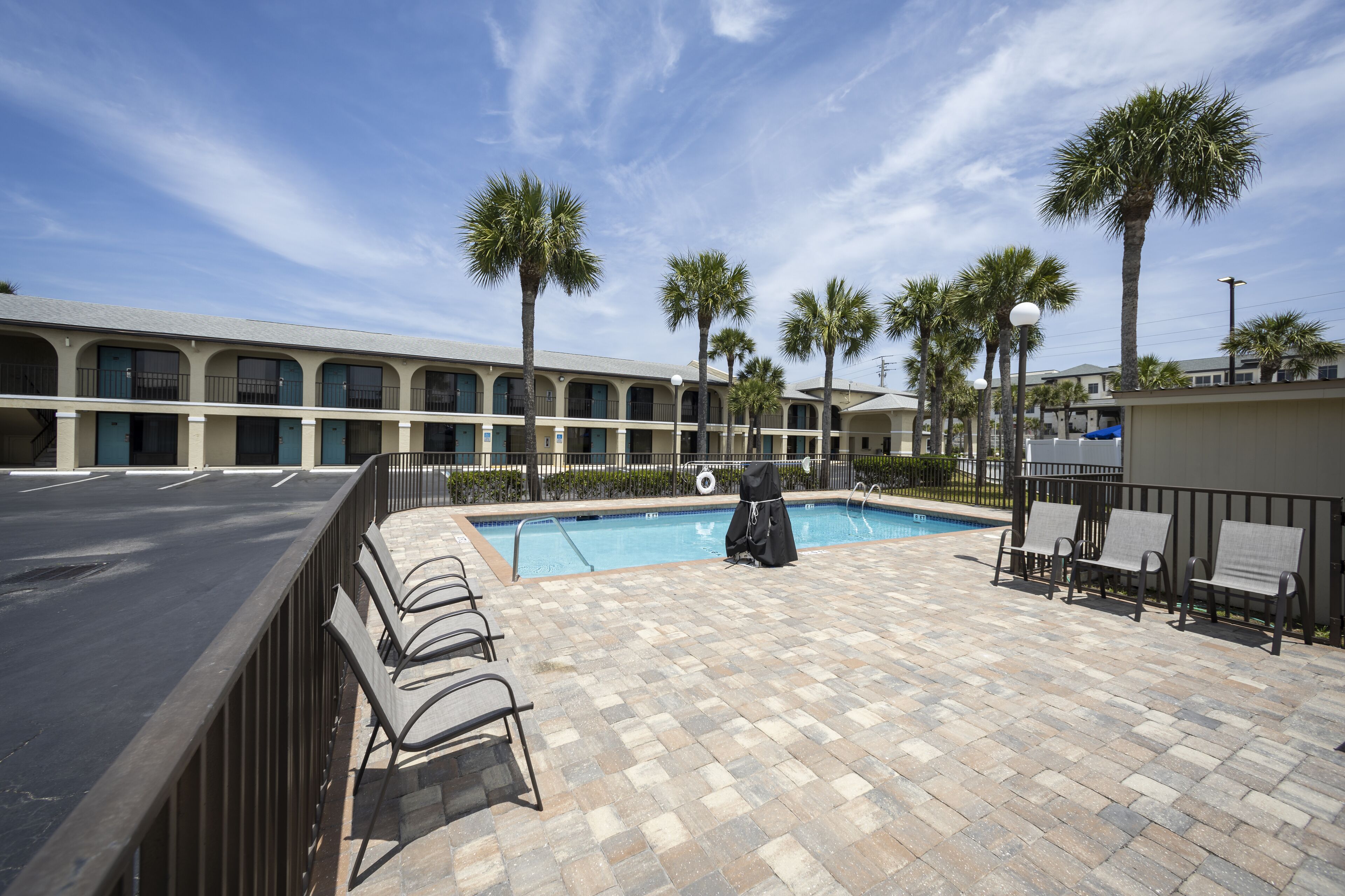A pool area with a tiled floor, lounge chairs, and a covered seating area.