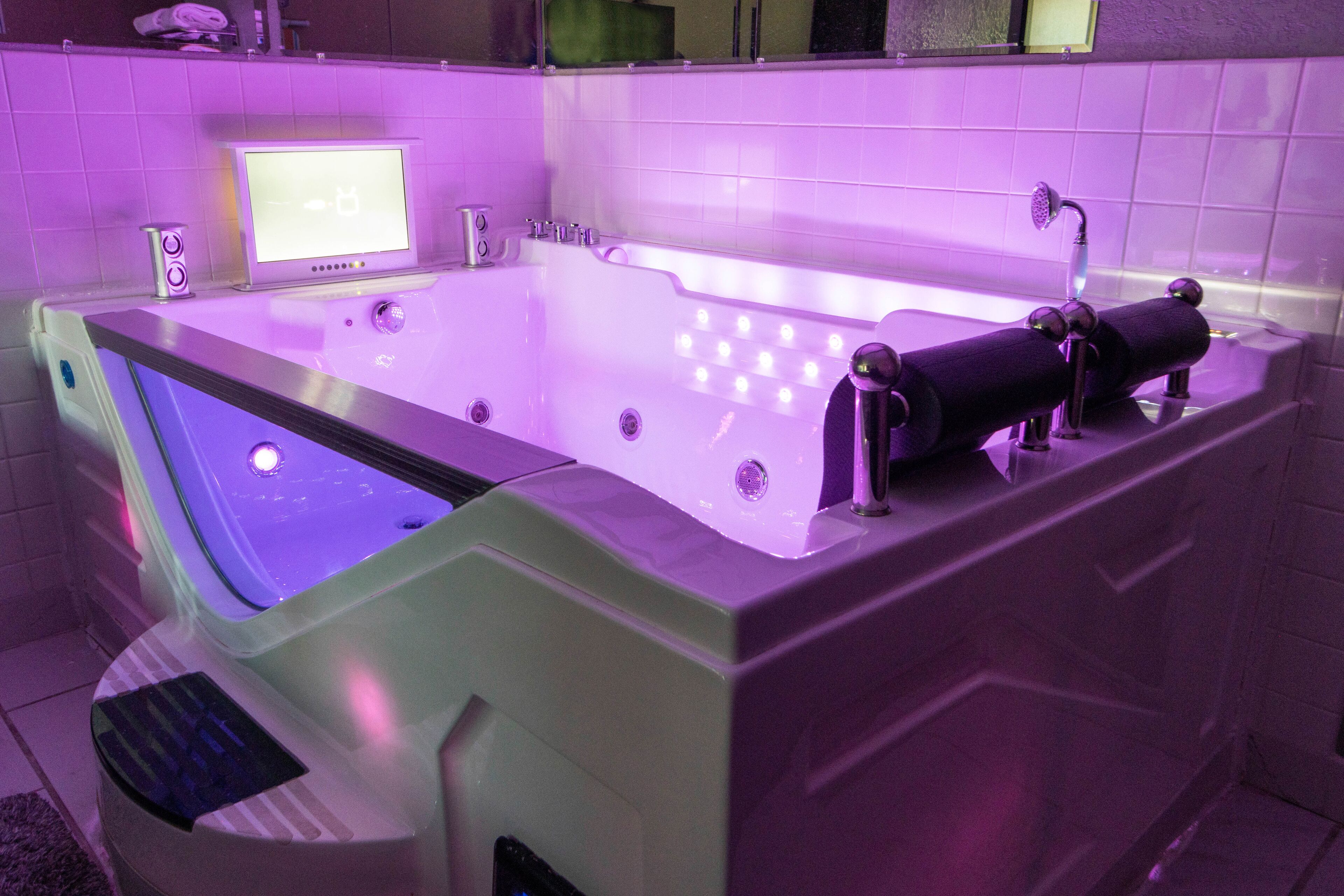 A modern spa tub with a digital display, built-in speakers, and a handheld showerhead.