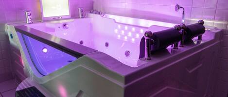 A modern spa tub with a digital display, built-in speakers, and a handheld showerhead.