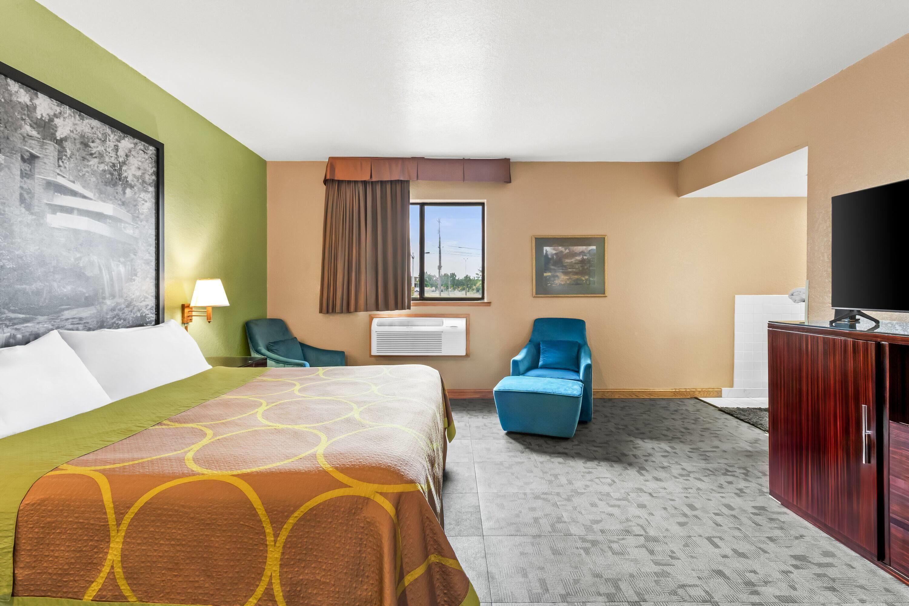 Een hotelkamer met een bed, twee stoelen, een televisie en een bureau.
