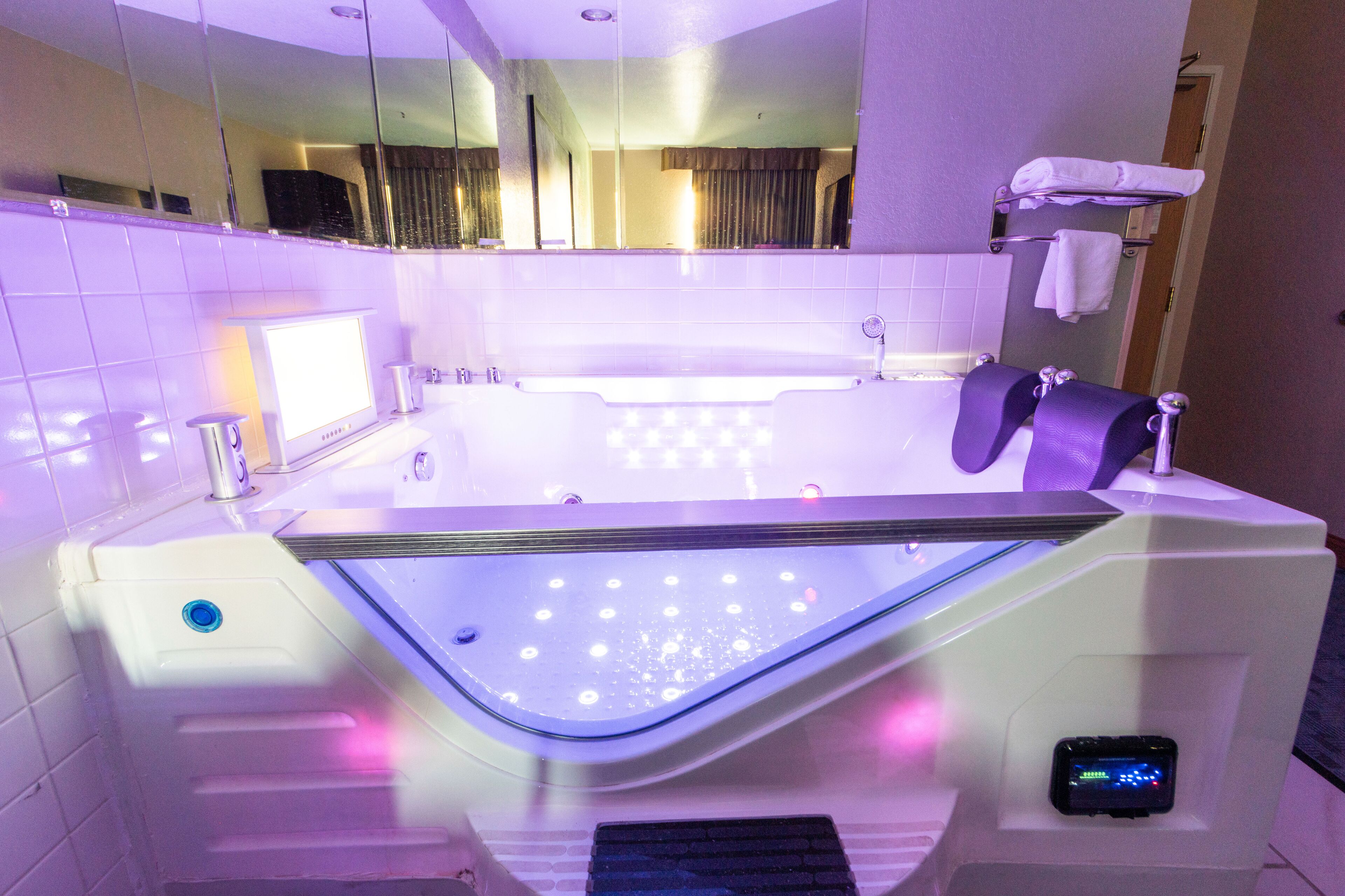 Une salle de bain moderne dotée d’une grande baignoire, d’un miroir et d’un panneau de commande numérique.