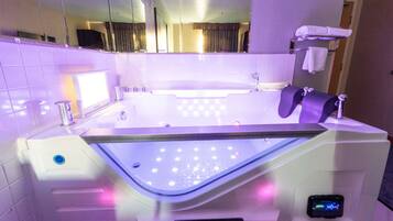 Une salle de bain moderne dotée d’une grande baignoire, d’un miroir et d’un panneau de commande numérique.