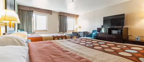 Ein Hotelzimmer mit zwei Betten, einem Schreibtisch, einem Stuhl, einem Fernseher und einem Fenster.