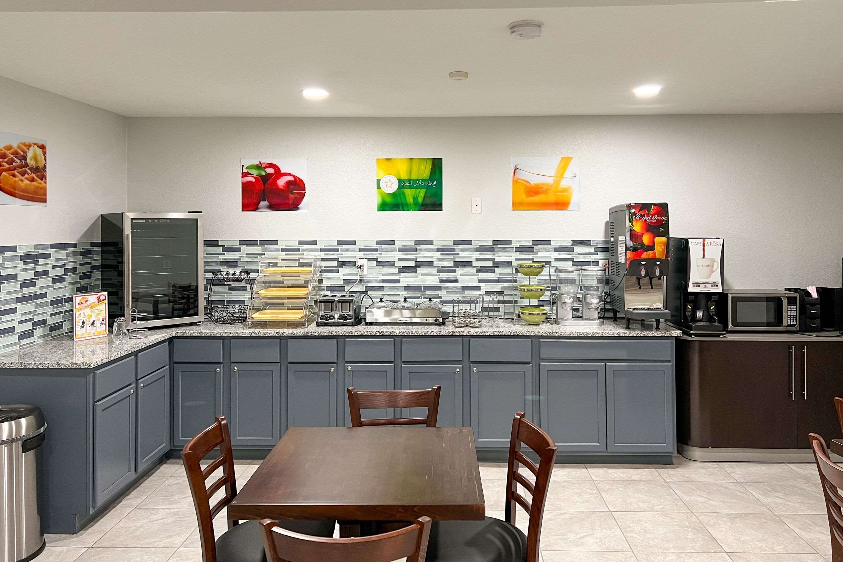 A modern kitchen with grey cabinets, a granite countertop, and various appliances including a coffee maker and microwave.