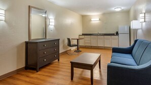 Un espacio habitable compacto con kitchenette, un aparador de color oscuro, un sofá azul y una pequeña mesa.