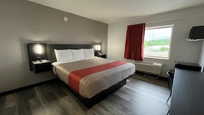 A hotel room with a large bed, bedside tables, a desk, a window with a view, and a wall-mounted TV. - Motel 6 Urbana, IL (Urbana)