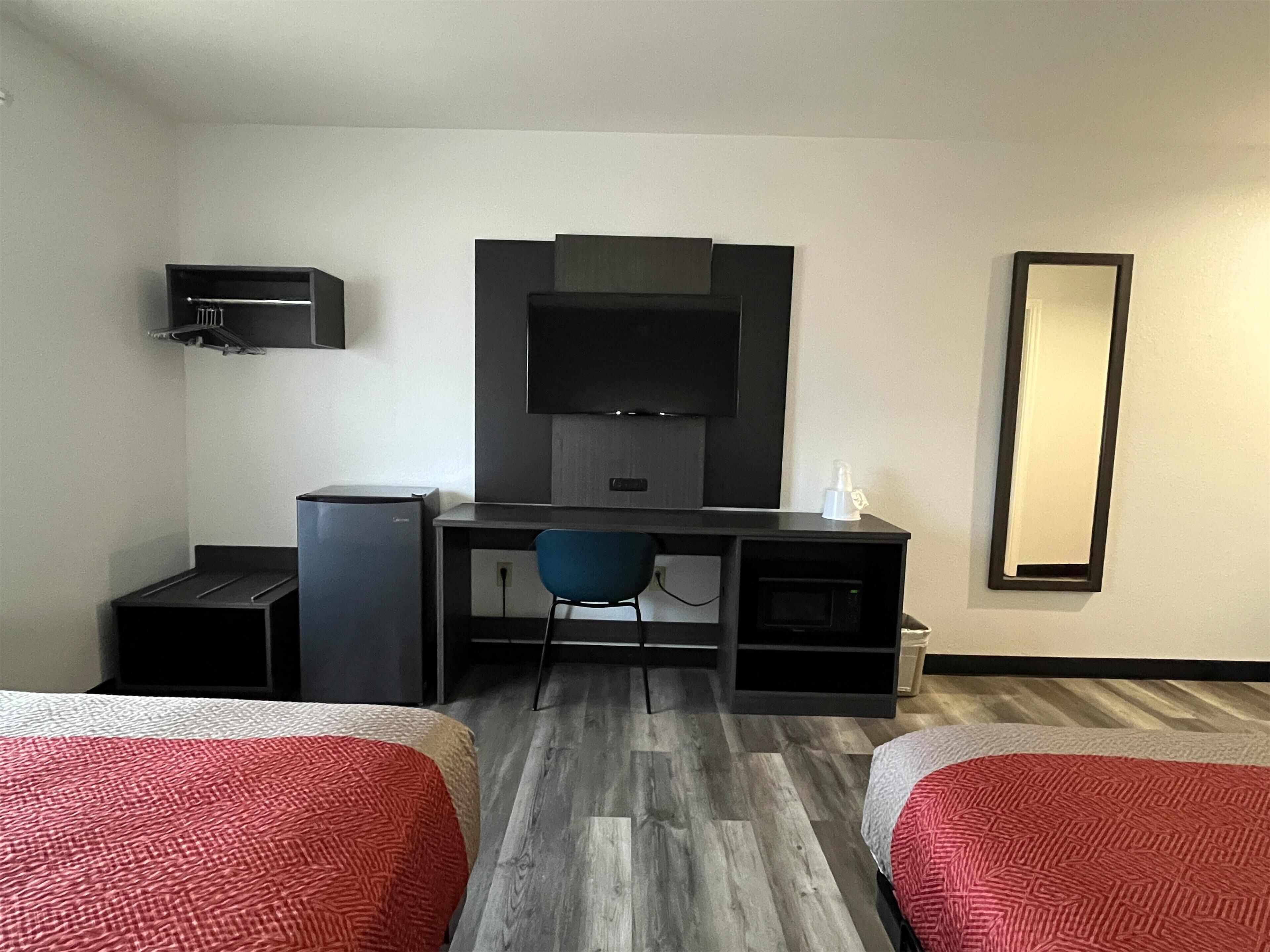 Habitació d'hotel amb dos llits, una taula de treball, una cadira, un televisor i un mirall.