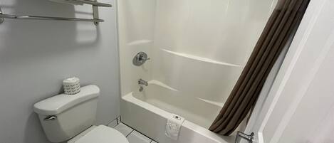A small, clean bathroom with a toilet, a bathtub, and a shower.
