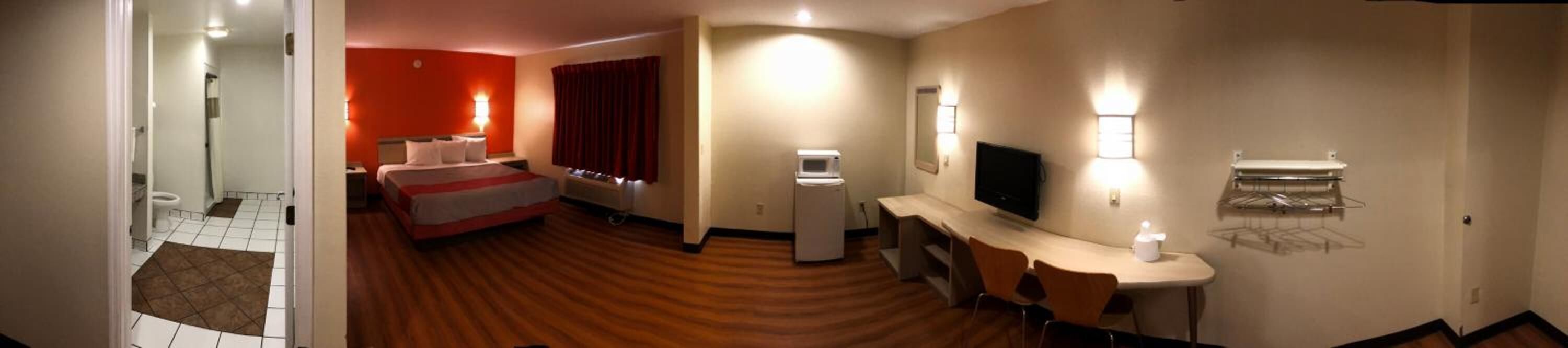 A hotel room with a bed, a desk, a TV, and a minibar.
