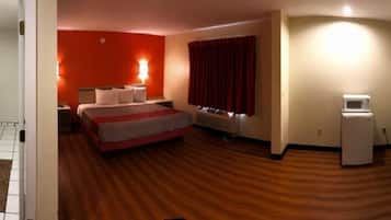 A hotel room with a bed, a desk, a TV, and a minibar.