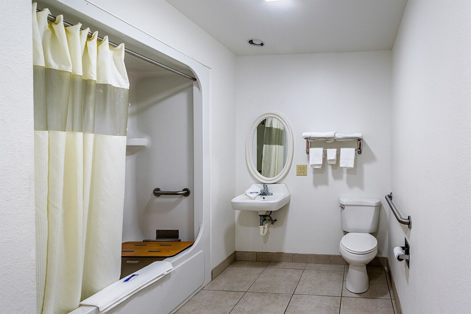 Un bagno piccolo e bianco con doccia, WC e lavandino.