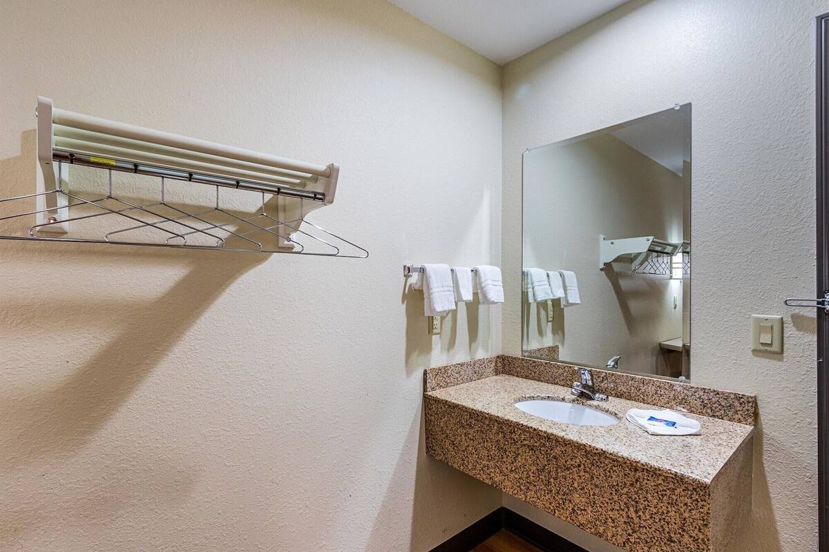 A bathroom with a granite countertop sink, a mirror, and a towel rack.