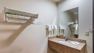 A bathroom with a granite countertop sink, a mirror, and a towel rack.