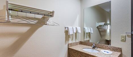 A bathroom with a granite countertop sink, a mirror, and a towel rack.