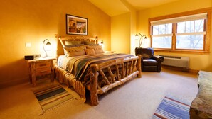 A bedroom with a wooden bed, a chair, a nightstand, a window, and a picture on the wall. - Niwot Inn & Spa (Longmont)