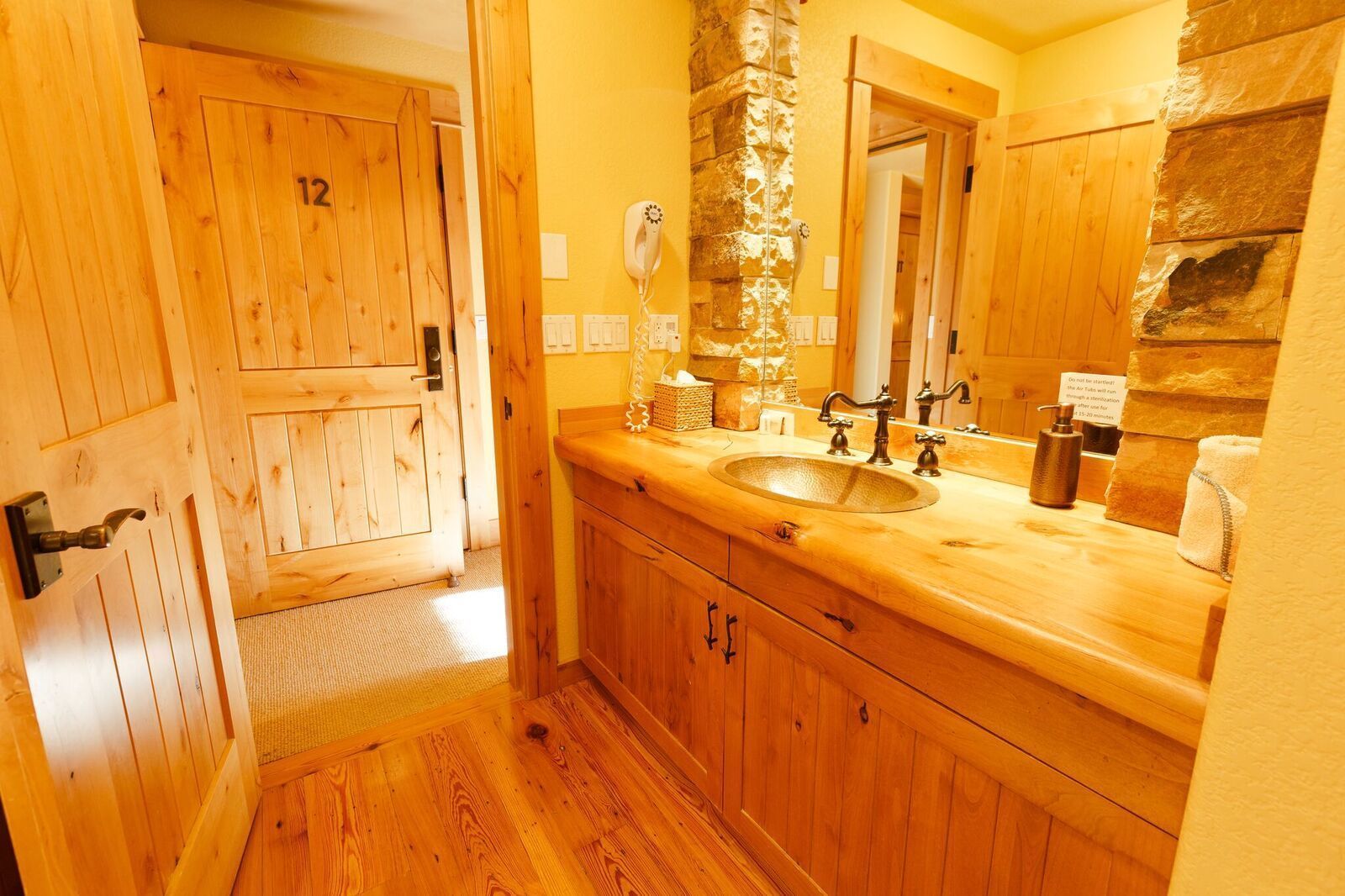 A wooden bathroom with a sink, mirror, and towel rack.