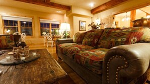A cozy living room with a wooden coffee table, a patterned sofa, and a dining area with a chair and table. - Niwot Inn & Spa (Longmont)