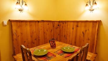 Una cabana de fusta amb dues làmpades, una taula amb dos plats verds i una gerra.