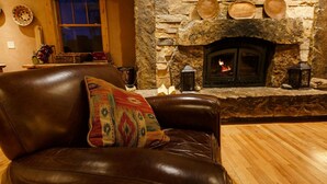 A cozy living room with a stone fireplace, leather sofa, and a patterned throw pillow. - Niwot Inn & Spa (Longmont)