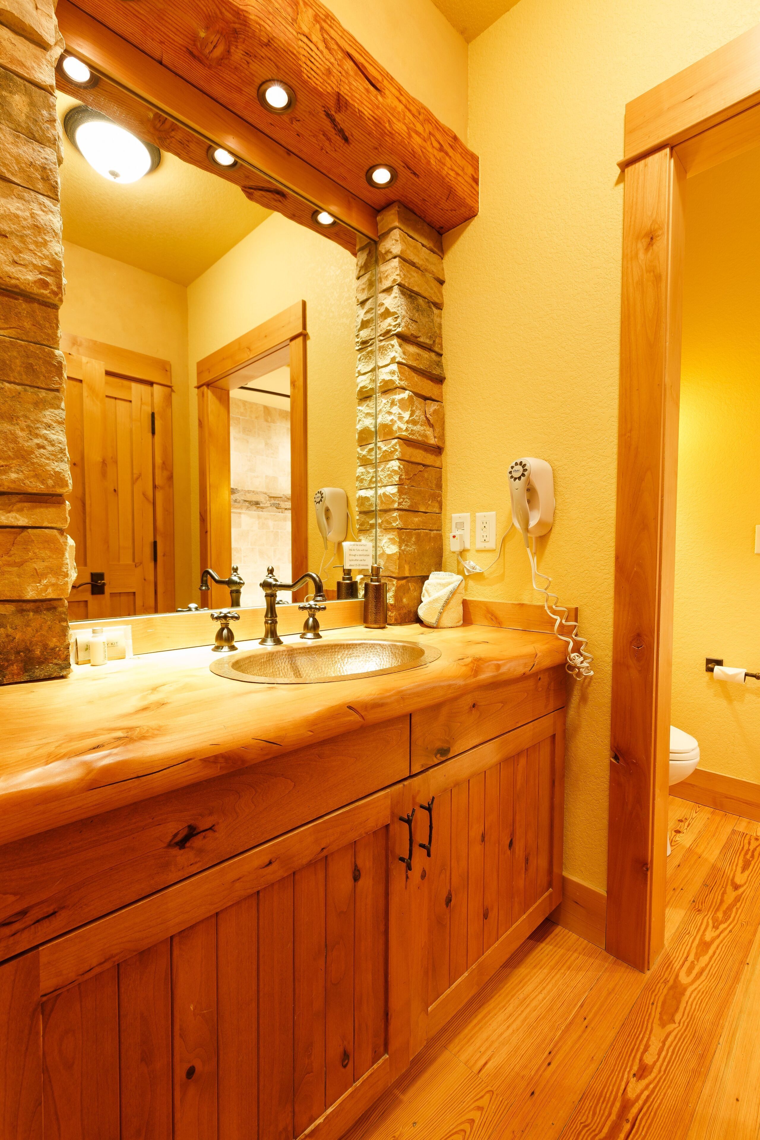 A wooden bathroom vanity with a large mirror, a hairdryer, and a towel rack.