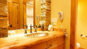 A wooden bathroom vanity with a large mirror, a hairdryer, and a towel rack.