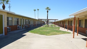 A motel with a central courtyard, palm trees, and a covered walkway. - Gateway Inn (Red Bluff)