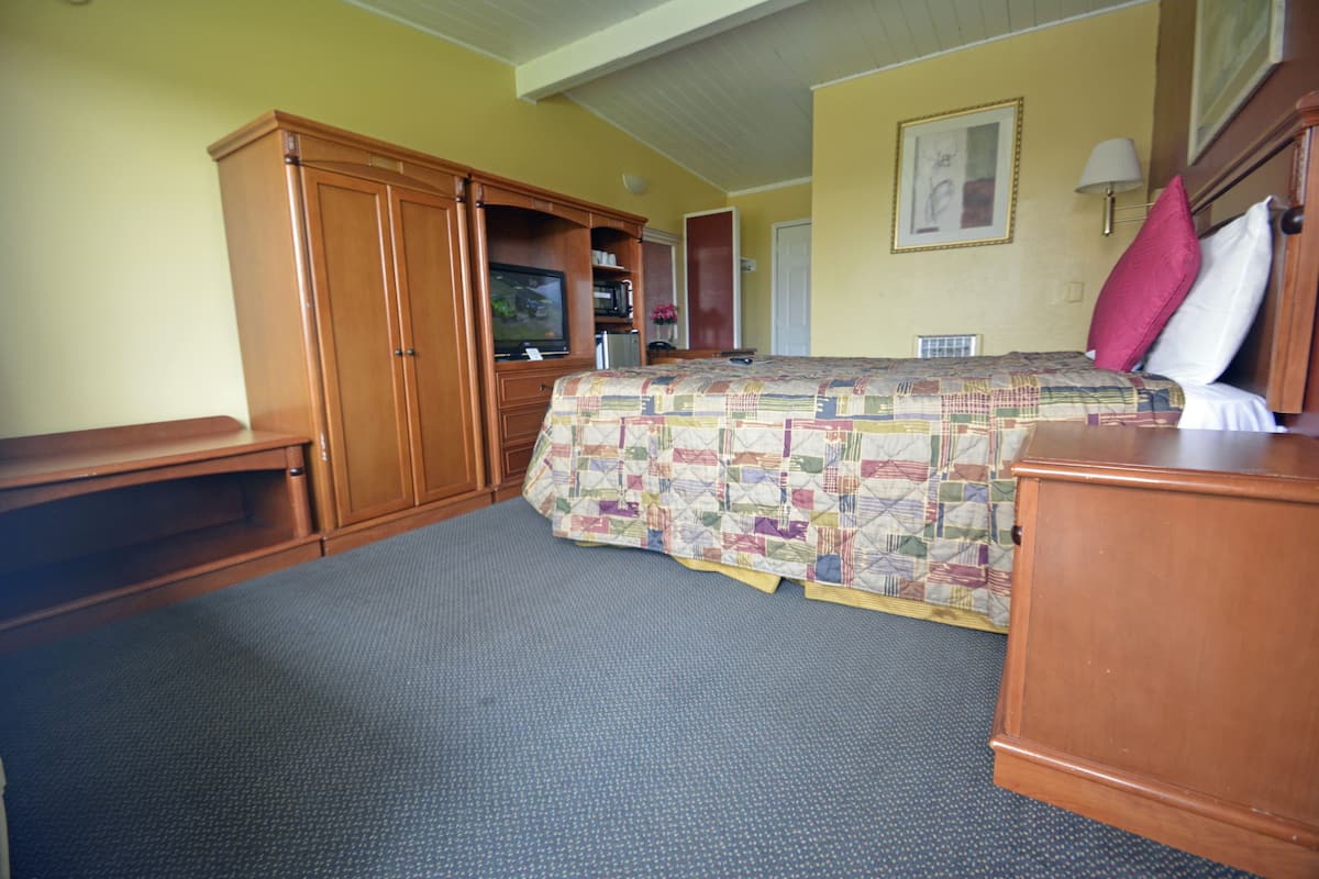A bedroom with a bed, wooden wardrobe, and a television.
