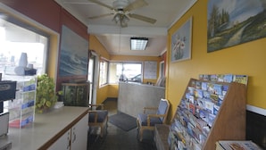 A reception area with a desk, chairs, a bulletin board with travel brochures, and a ceiling fan. - Gateway Inn (Red Bluff)