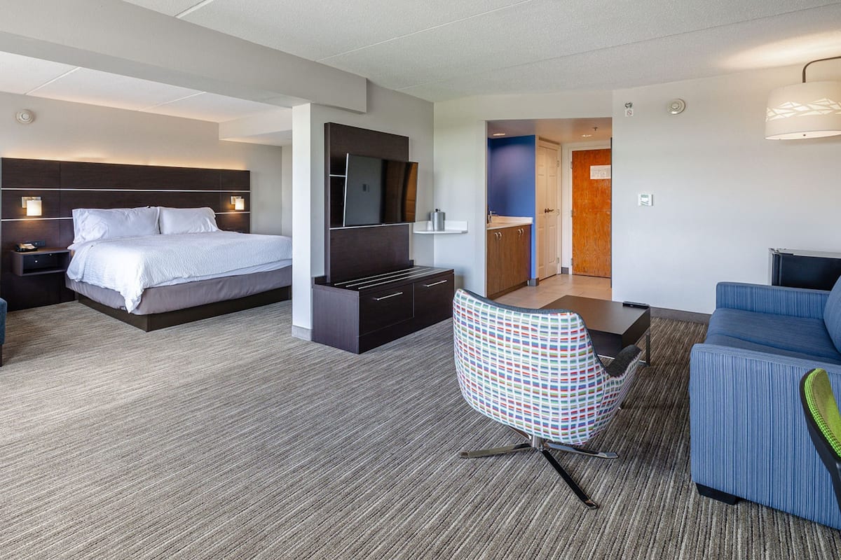 A hotel room with a bed, a desk, a TV, a chair, and a sofa.