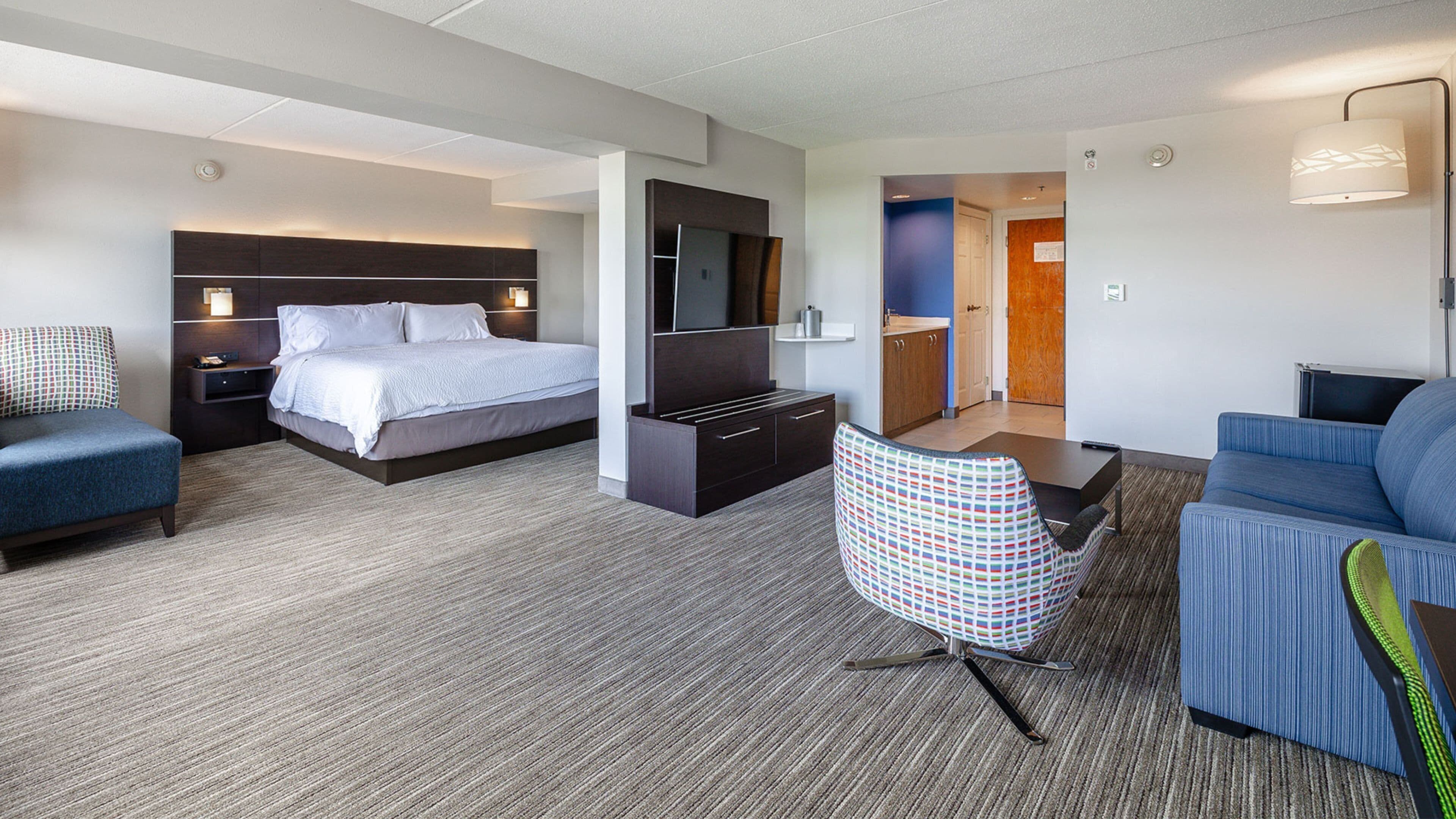 Ein Hotelzimmer mit einem Bett, einem Schreibtisch, einem Fernseher, einem Sessel und einer Couch.