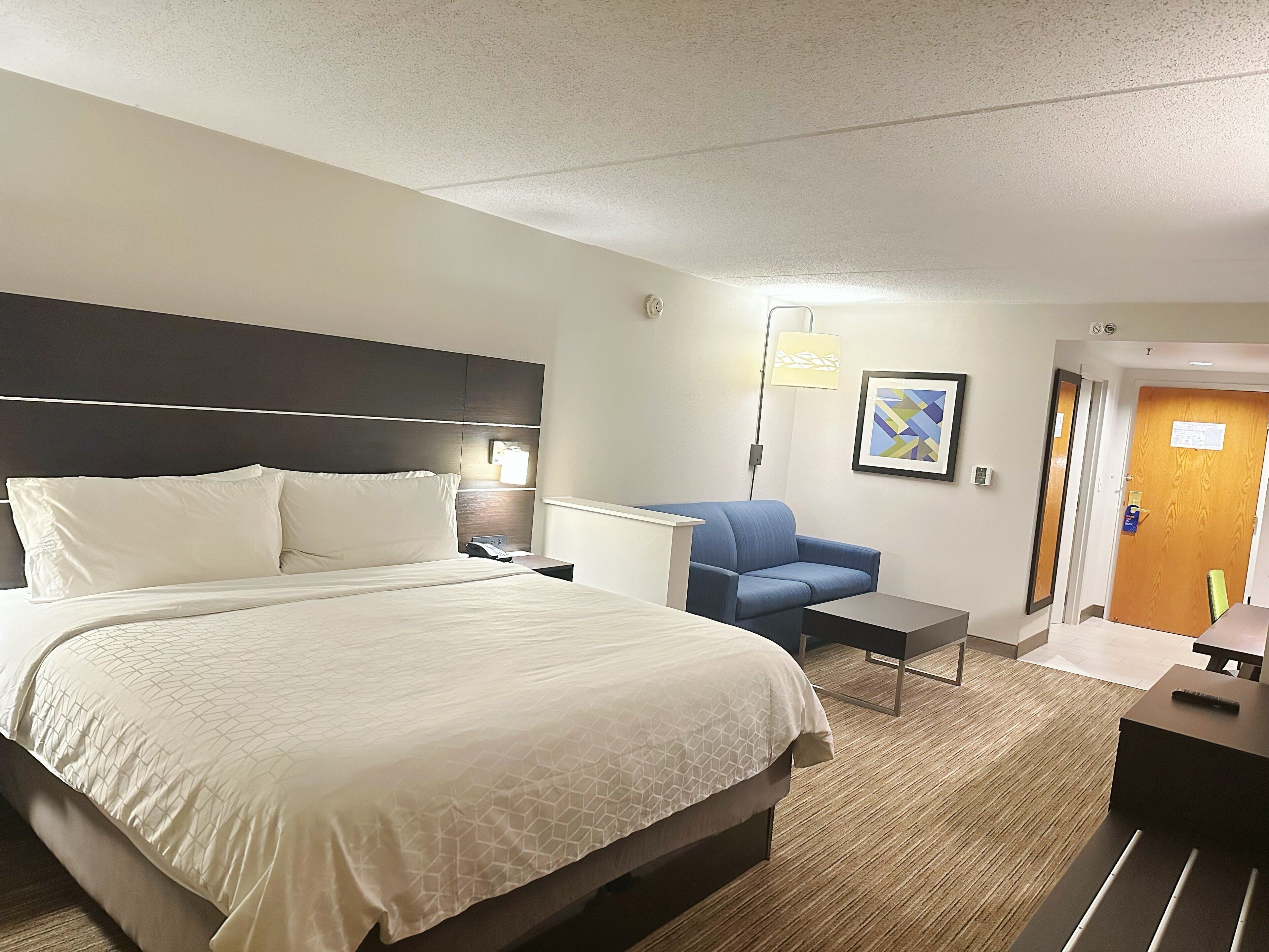 Habitación de hotel con una cama grande, un escritorio, una silla y una puerta.