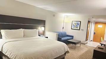 Habitación de hotel con una cama grande, un escritorio, una silla y una puerta.