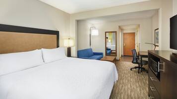 A hotel room with a large bed, a desk, a chair, a television, and a mirror.