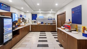 A modern kitchen with a refrigerator, coffee machine, and a bakery display. - Holiday Inn Express & Suites Jacksonville SE- Med Ctr Area by IHG (Jacksonville)