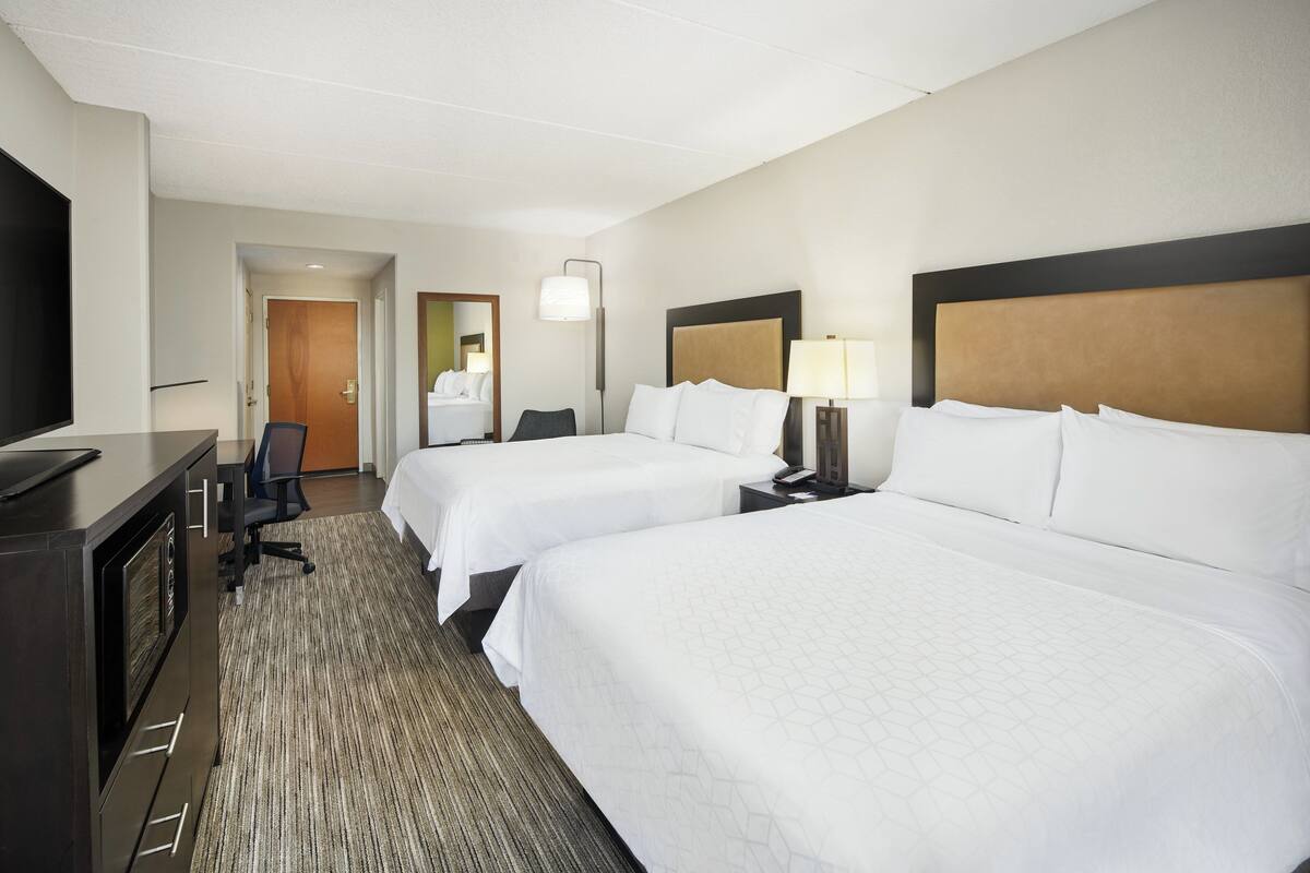 Une chambre d’hôtel avec deux lits, un bureau, une télévision et un miroir.