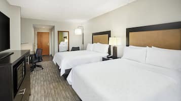 A hotel room with two beds, a desk, a TV, and a mirror.