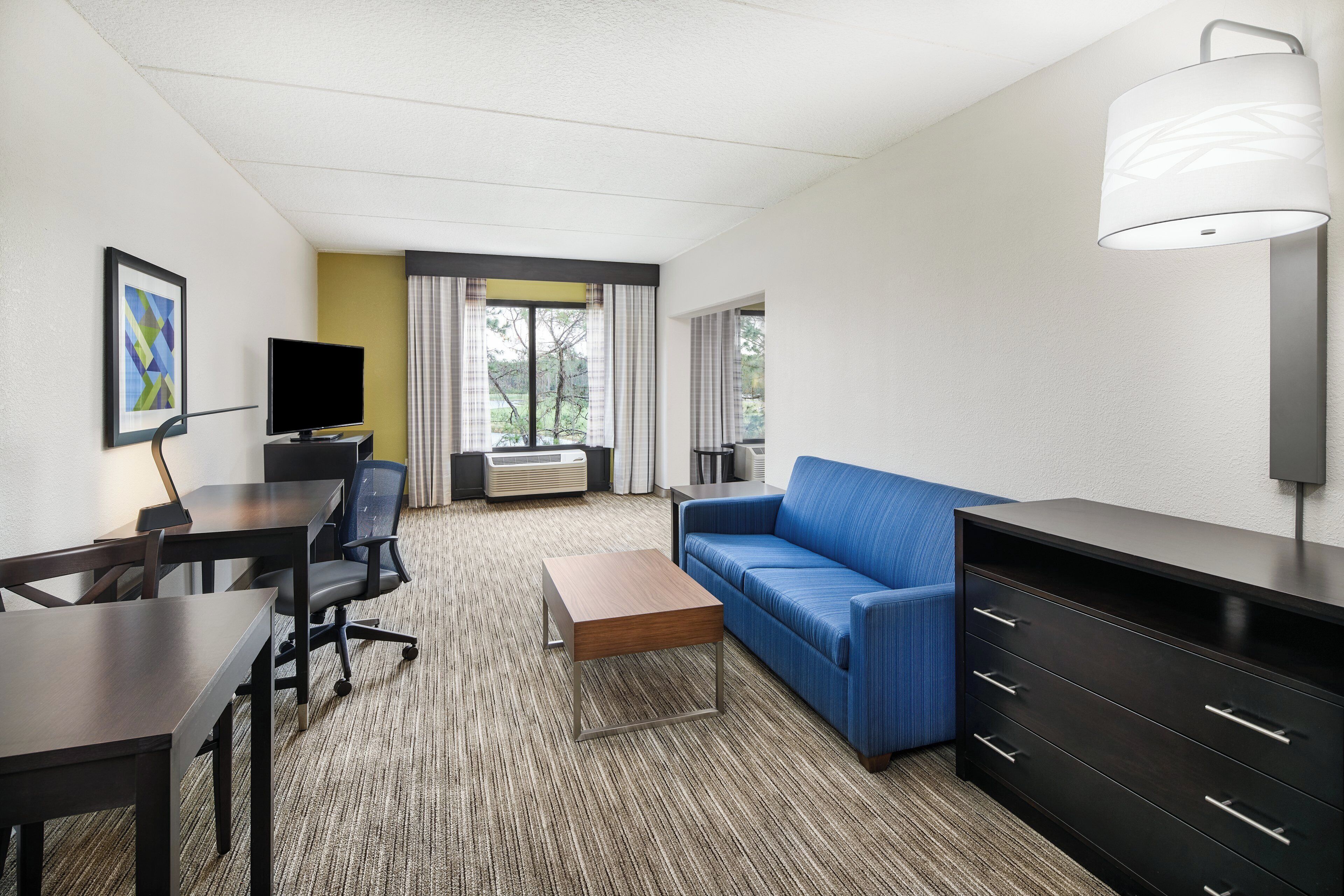 Habitación de hotel con escritorio, silla, sofá y televisor.
