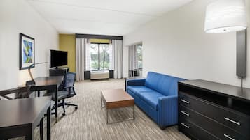 Habitación de hotel con escritorio, silla, sofá y televisor.