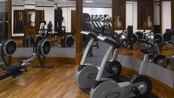 Un gimnasio con máquinas de cardio, bancos de pesas y espejos.
