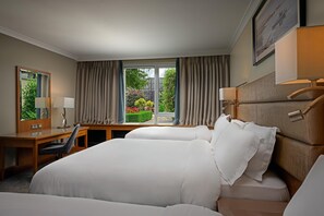 A hotel room with a large bed, a desk, a chair, a mirror, and a window with curtains.