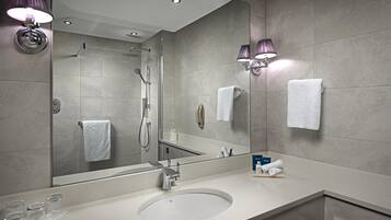 A modern bathroom with a large mirror, a sink, and a shower.